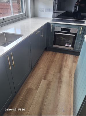 Blue kitchen cabinetry with gold handles and integrated oven