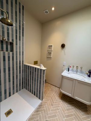 Bathroom renovation with blue striped tiled walk-in shower and marble vanity