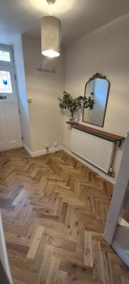 Entrance hallway with herringbone flooring and radiator cover shelf
