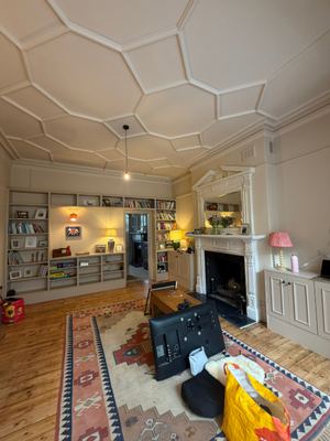 Living room with decorative geometric ceiling and period fireplace