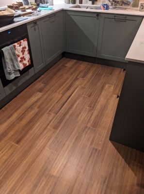 Sage green kitchen cabinetry with wood flooring
