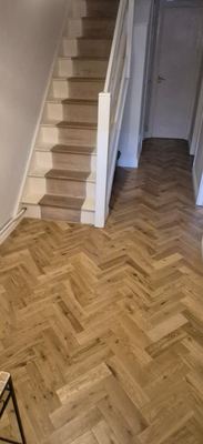 New stair carpet runner leading down to herringbone flooring in hallway