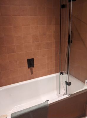 Bathroom with terracotta wall tiles and bath shower screen